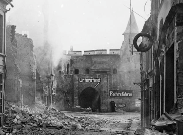 The smouldering ruins of a street in Cambrai, three days after the British entry, 10 October 1918. Note German notices indicating an air raid shelter and the direction to the citadel. IWM © Q11804
