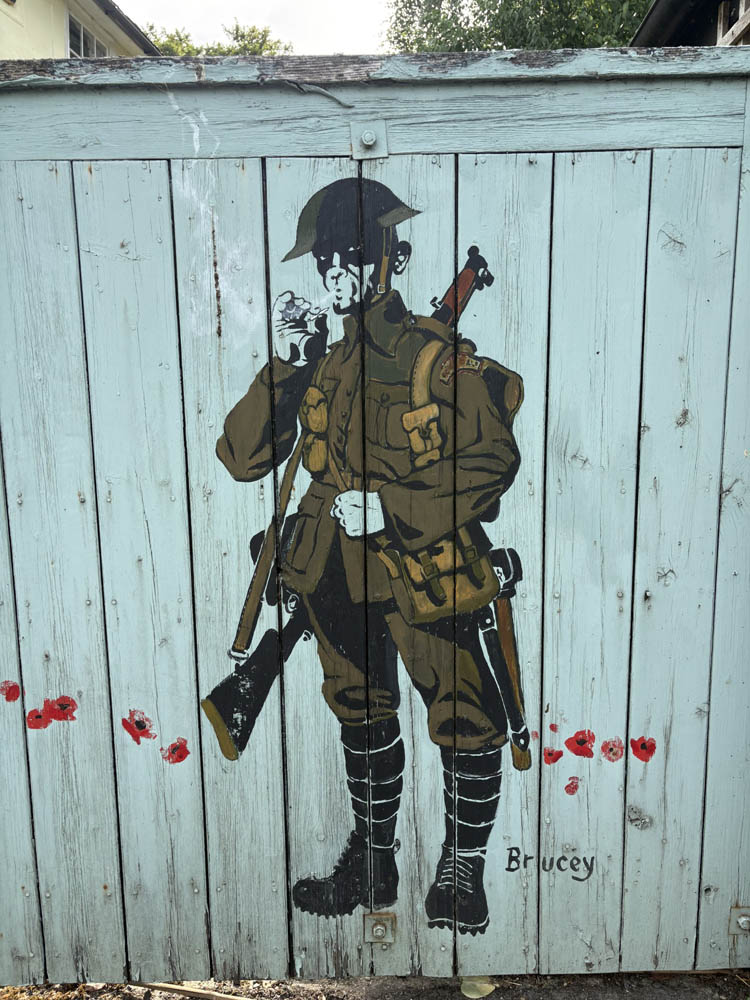Mural on a gate of a Tommy, fully armed, drawing on his cigarette