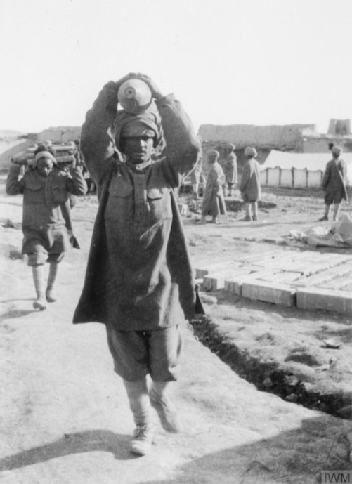 Men of an Indian labour unit carrying artillery shells at an ammunition dump in Mesopotamia. © IWM HU 99715