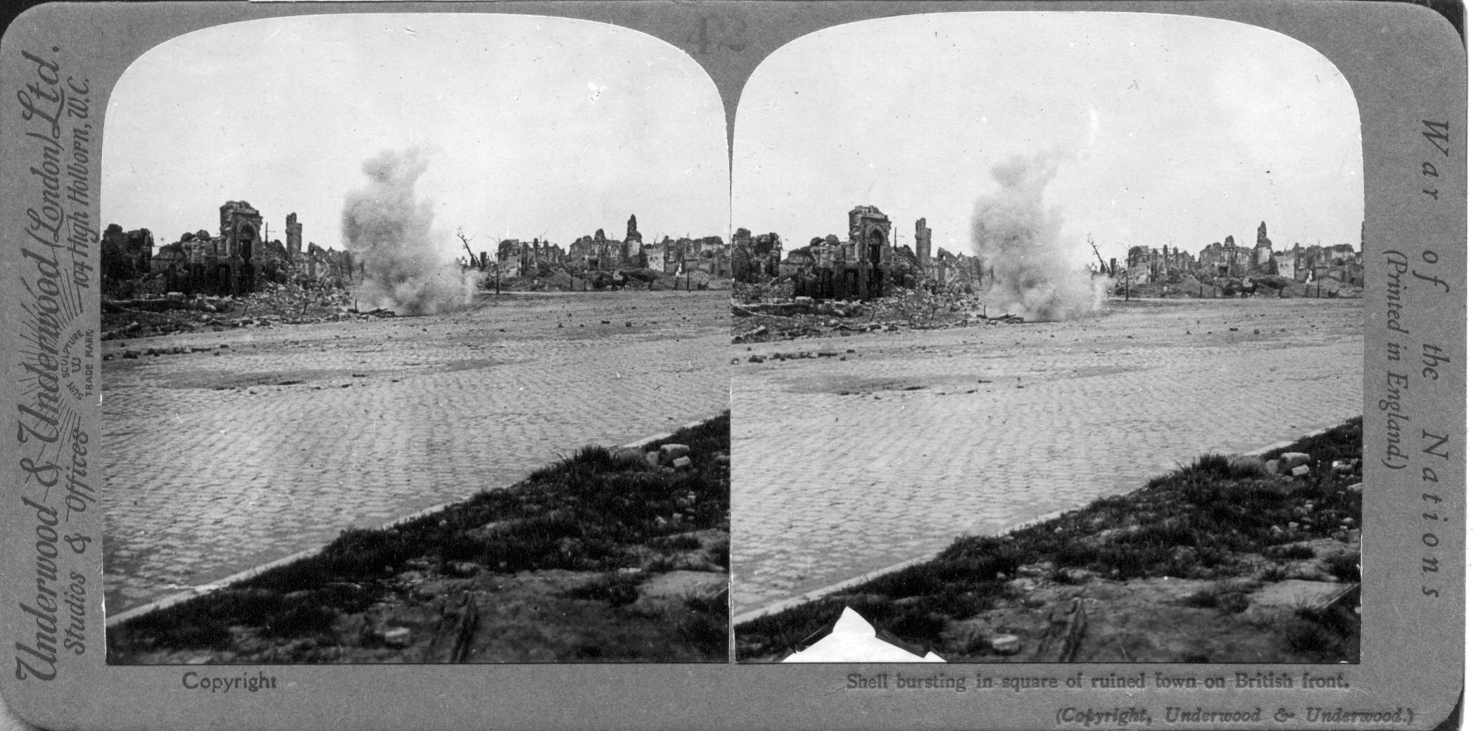 Shell bursting in square of ruined town on British front