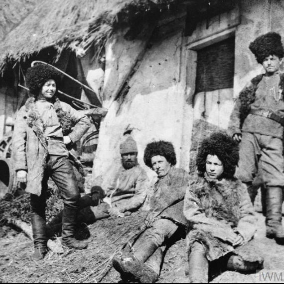 Russian Cossack troops in winter uniforms outside their accommodation huts. © IWM Q 98429