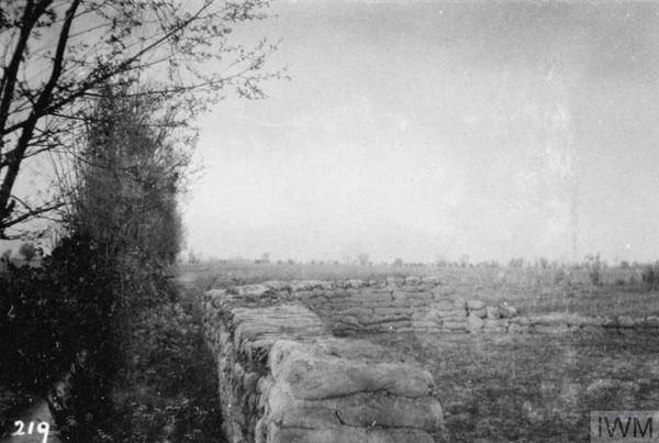 View of the Battle of Aubers Ridge, attack on Fromelles. During the bombardment (which began at 0500) at 0520, 9th May 1915. Smoke is rising from the German lines. Captain Claud Garrett Salmon of the 2nd Battalion, Cameronians (Scottish Rifles), was wounded in this breastwork and was killed whilst being removed. © IWM Q 51624