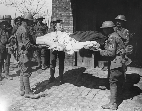 Battle of Hazebrouck. Men of the 2/7th Battalion, Royal Warwickshire Regiment, moving a bed-ridden elderly man of Robecq, 12 April 1918. © IWM Q 6511