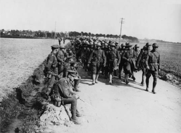 A column of American troops marching past British soldiers resting on the side of the road, France, in 1917 or 1918. source: National Library of Scotland, (259) L.602, http://digital.nls.uk/74548742.