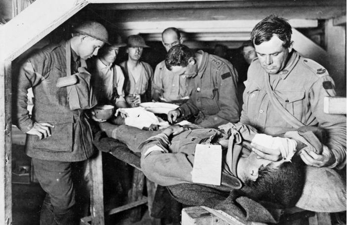 An Australian Medical Officer attends a wounded man at an Advanced Dressing Station during the Third Battle of Ypres (Passchendaele).© IWM E(AUS) 714
