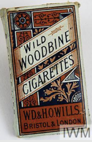 Rectangular red and blue-printed green paper packet containing five "WILD WOODBINE CIGARETTES".© IWM EPH 2736