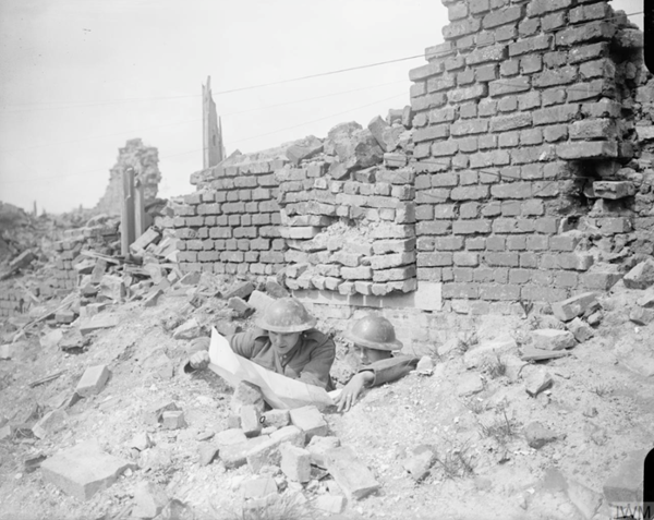 Two men of the King's Royal Rifle Corps (20th Division) checking a map at the entrance to their dug out under a ruined house in Lievin, 14 May 1918.© IWM Q 6624