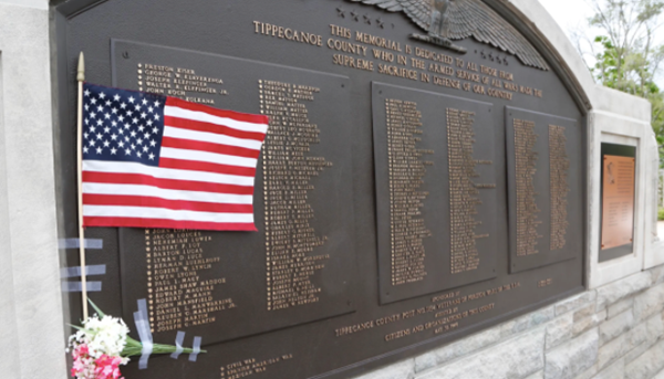 A small US flag and flowers taped to the memorial dedicated to all from Tippecanoe County who have made the supreme sacrifice in defense of the country next to Memorial Island Friday, May 27, 2016, in Columbian Park.