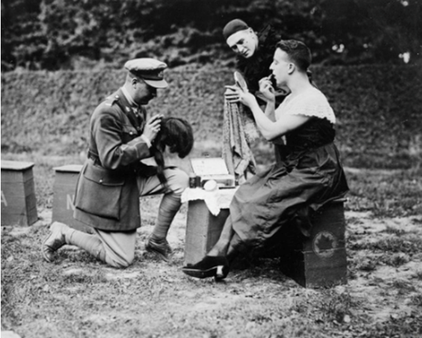 A female impersonator of the "Maple Leaves", the Canadian Concert Party, making up for his role in a field on the Western Front.  © IWM CO 2013