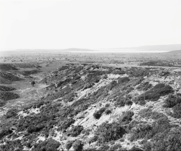 Looking down Kaiajik Dere showing Turkish trenches on the right and Australian trenches on the left of Dere, Hill 60 in in the centre. Suvla Bay and Salt lake are in the distance directly behind Hill 60, looking north west. One of a series of photographs taken on the Gallipoli Peninsula under the direction of Captain C E W Bean of the Australian Historical Mission, during the months of February and March, 1919