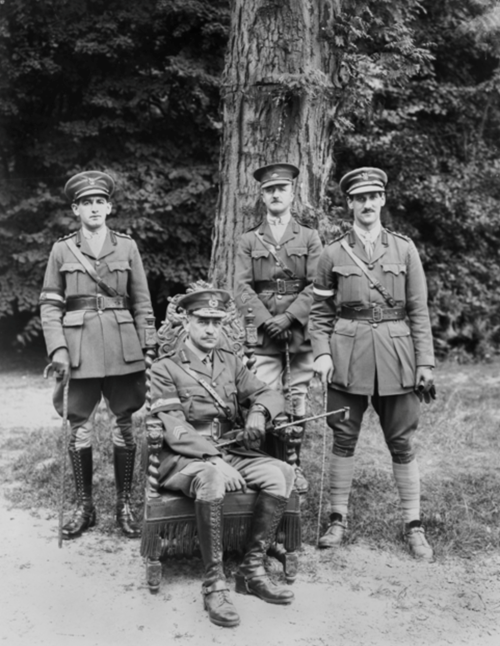 Lieutenant General Sir John Monash KCB VD, Australian Corps Commander (seated), with his two Aides-de-Camp (ADC) and the Camp Commandant, at the Australian Corps Headquarters. Identified standing, left to right: Captain (Capt) A M Moss, ADC; Major W W Berry, Camp Commandant, and Capt P W Simsonson, ADC. CC BY 4.0 Australian War Memorial E03186