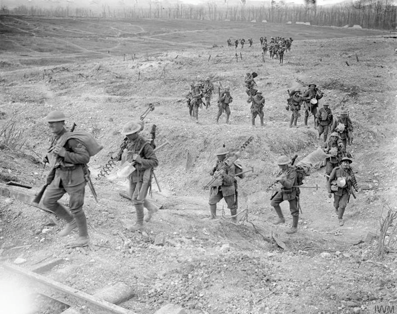A British wiring party carrying corkscrew wire pickets about to cross the railway line between Arras and Feuchy, May 1917 © IWM Q 5258