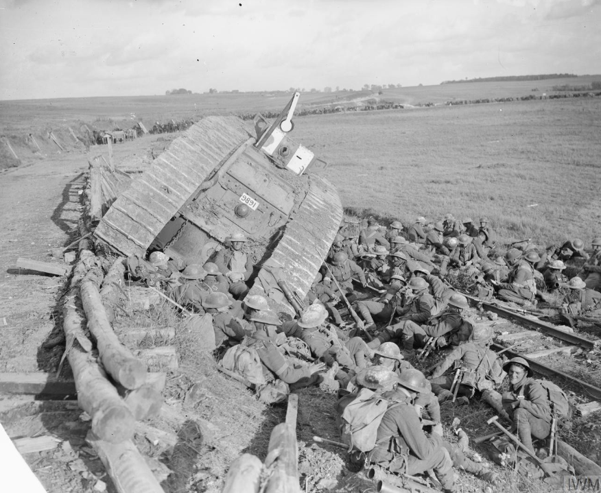 Battle of Cambrai. Men of the 20th Battalion, Manchester Regiment (25th Division) resting by a tank (serial number 9891), disabled by side-slipping down a railway embankment. Near Premont, 8 October 1918.