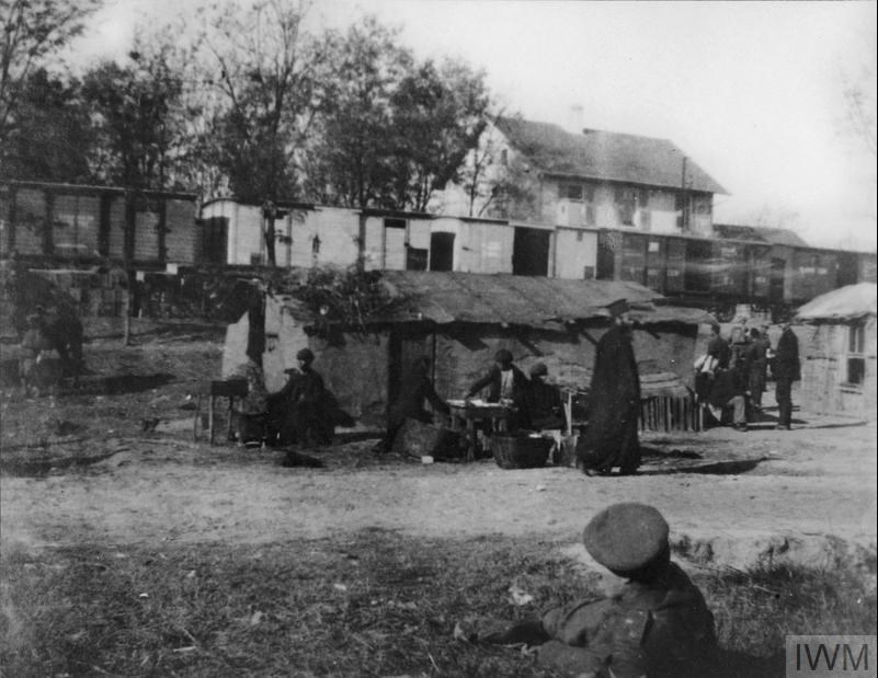 Troop Train Standing At Doiran Station Whilst Local Inhabitants Fry Fish Caught In Lake Doiran, November 1915. IWM Q 55118